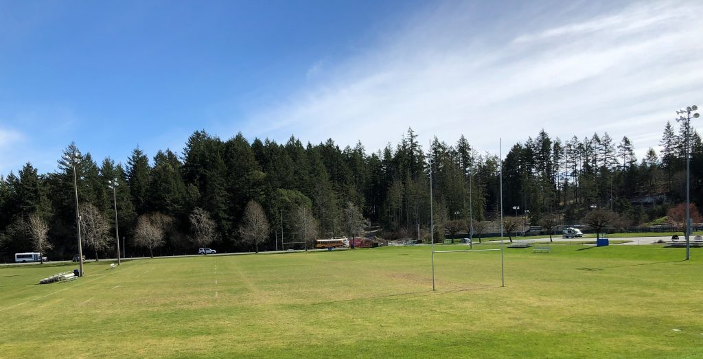 The rugby field at Juan de Fuca, posts up and trees behind, on a sunny day