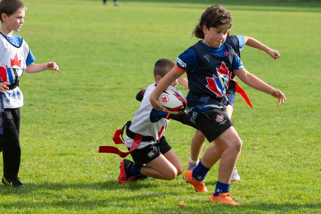Westshore minis playing flag rugby, a young player running with the ball